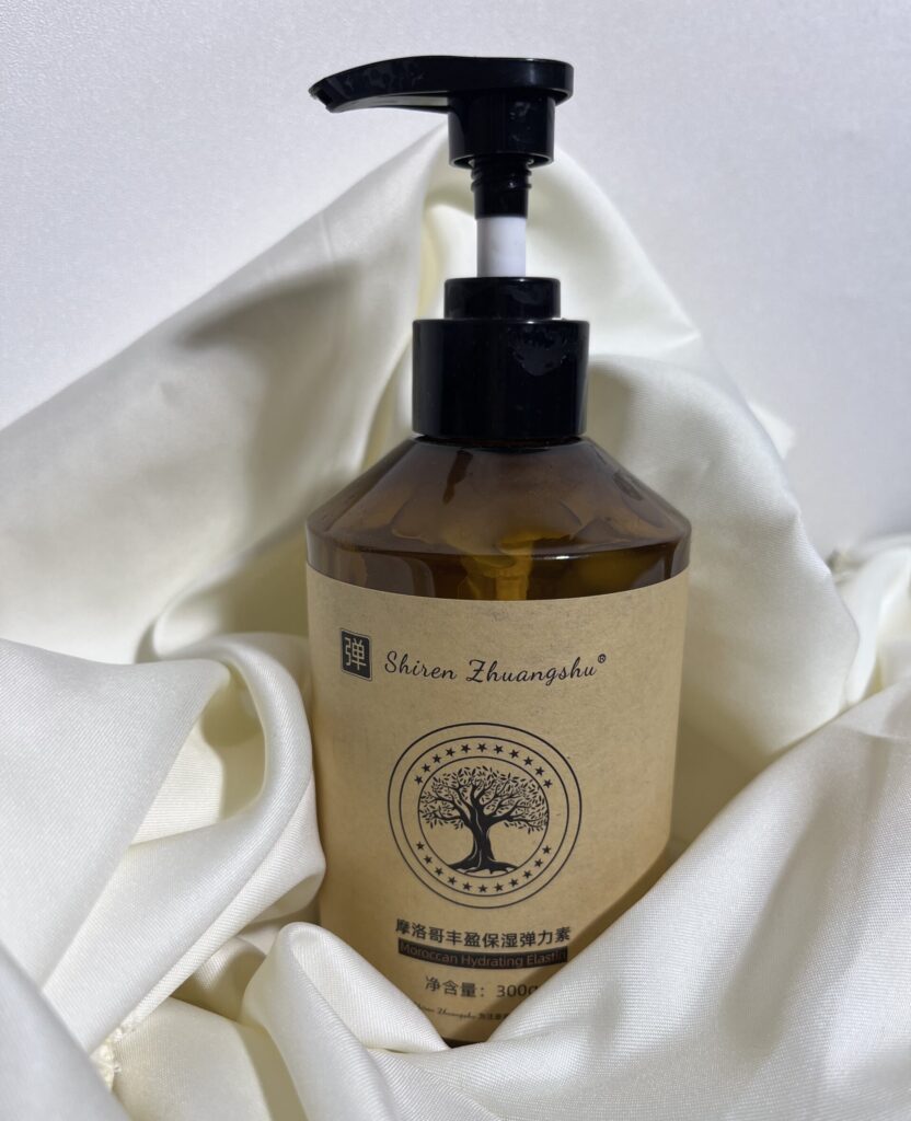 Moroccan Hydrating Elastin Curl Cream bottle on a clean background with white fabric