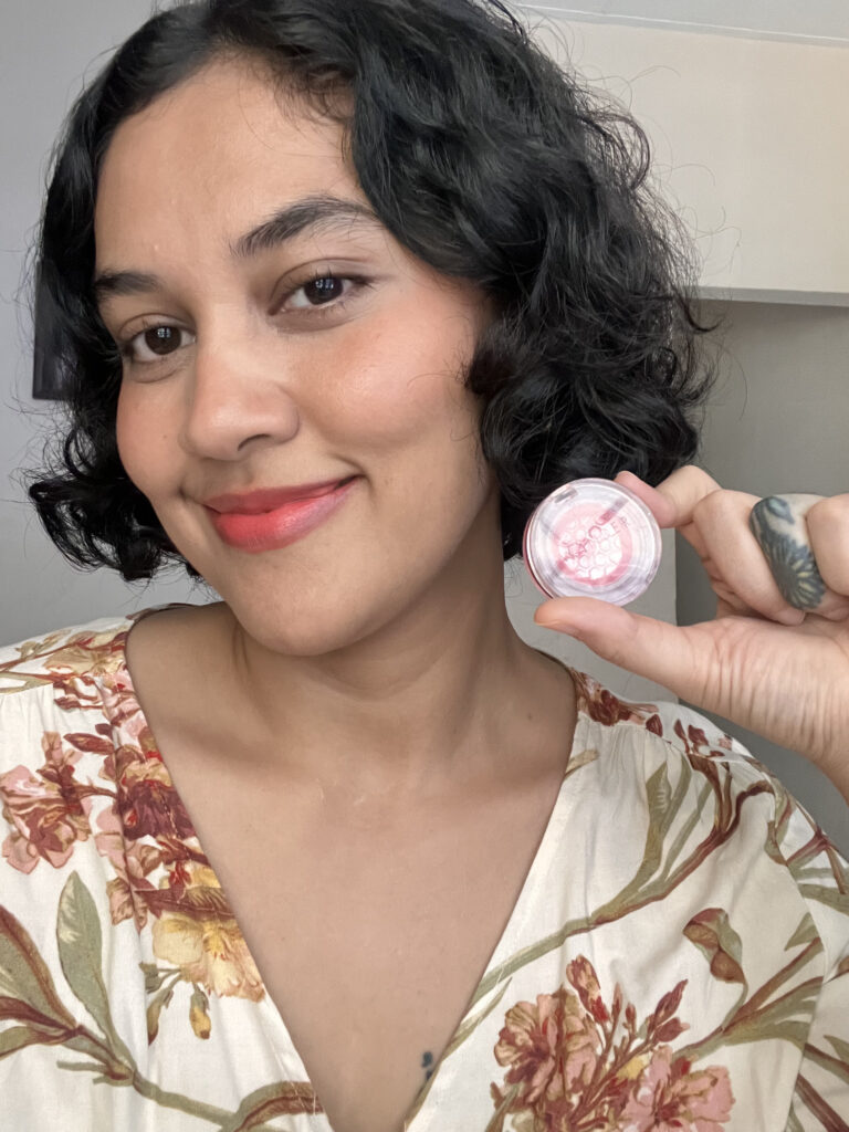 Full face wearing Wander Beauty Double Date Lip and Cheek Spring Fling while holding the product