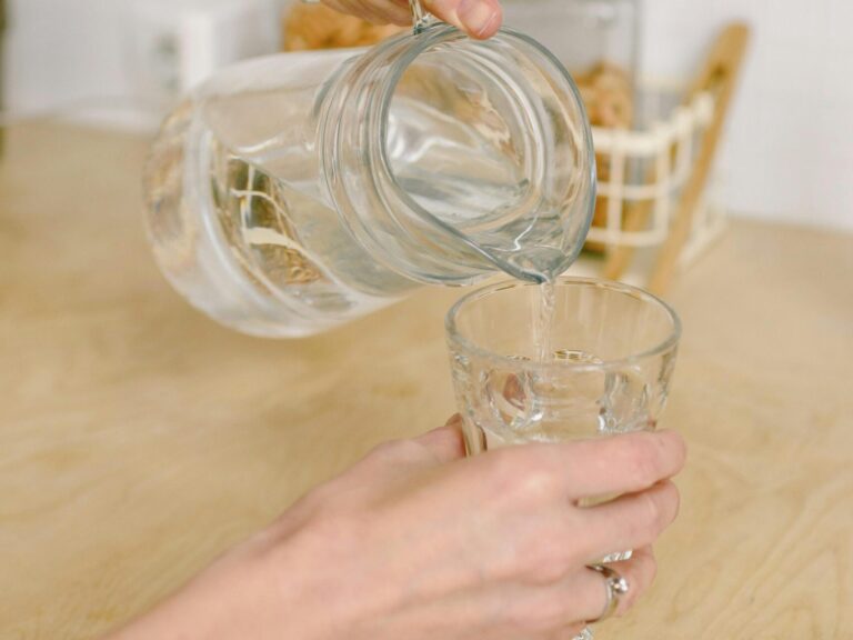 Hands pouring water into a glass representing hydration for skin health