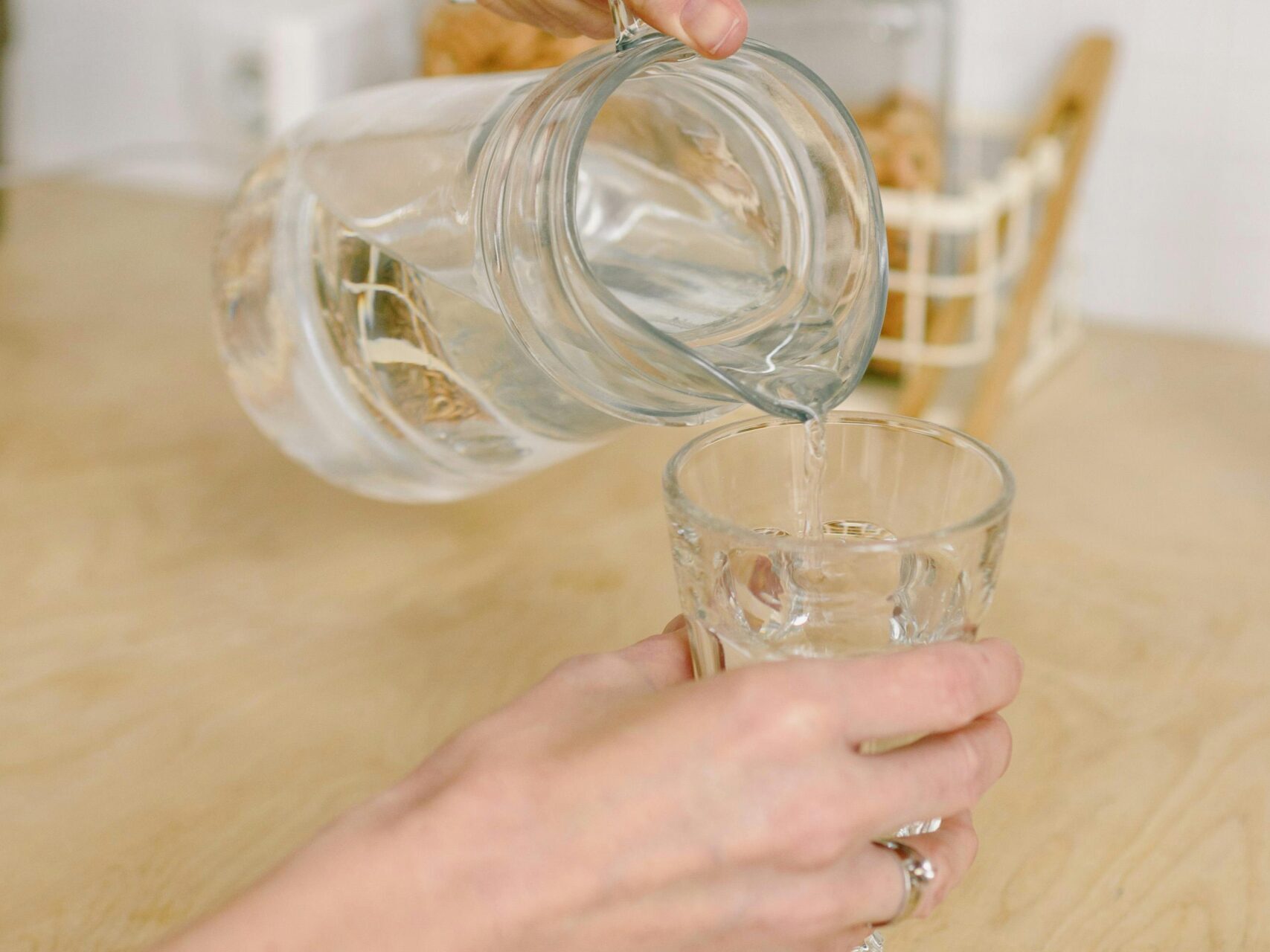 Hands pouring water into a glass representing hydration for skin health