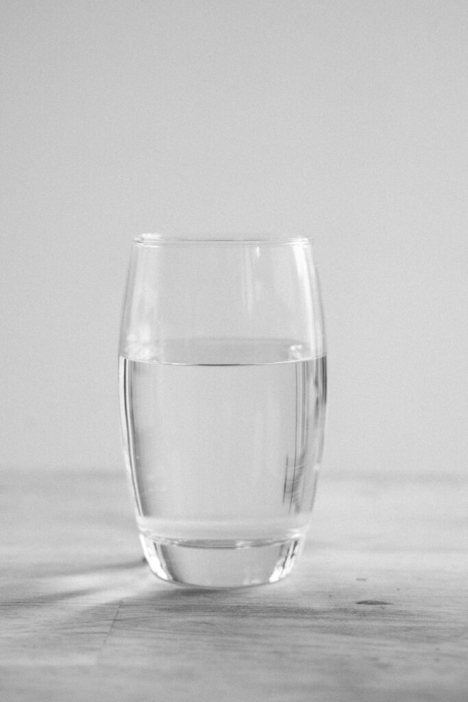 A simple, clear glass of water on a white surface, embodying a minimalist aesthetic.