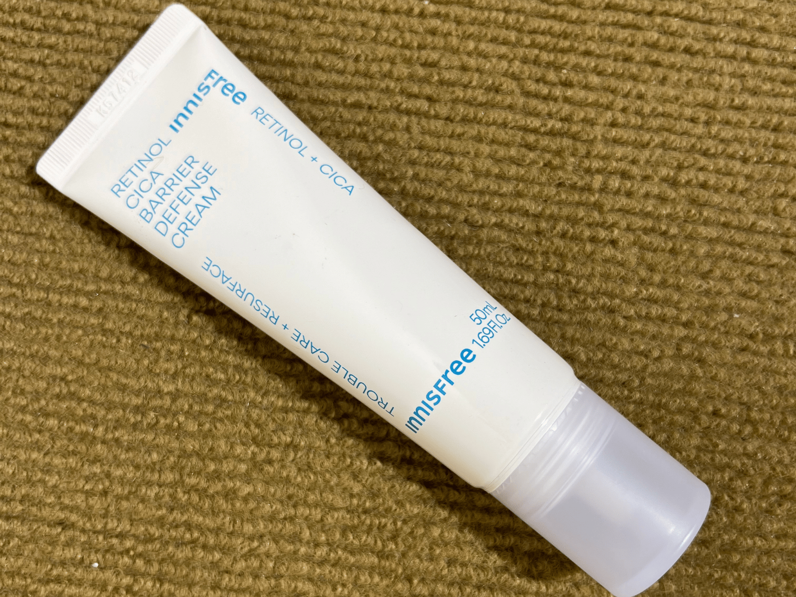 Innisfree Retinol Cica Barrier Cream tube displayed on a brown textured background.